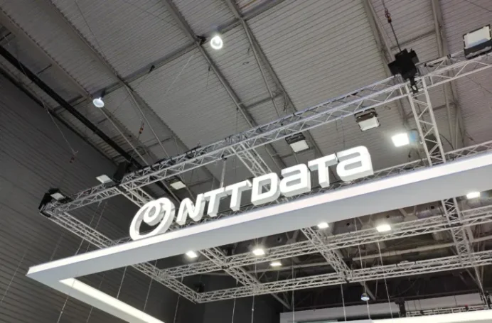 Panneau lumineux avec le logo de NTT Data dans un espace d'exposition.